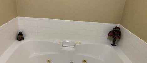 Une baignoire blanche avec un seul robinet, deux porte-savons et un porte-serviettes.