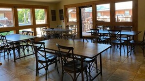 Un amplio comedor interior con varias mesas y sillas, ventanas grandes y vistas al exterior.