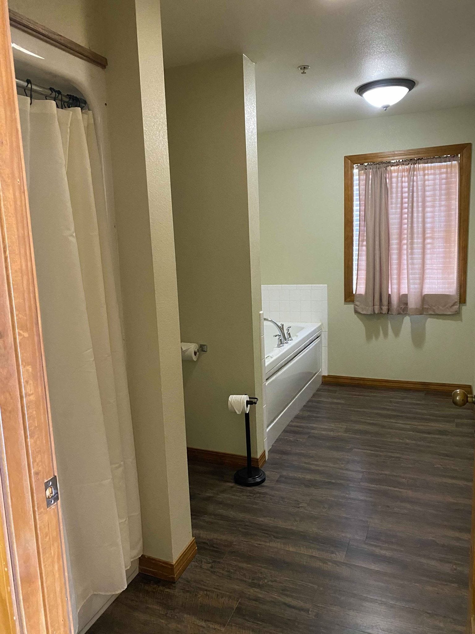 Un baño con inodoro, lavamanos y ventana con cortinas.