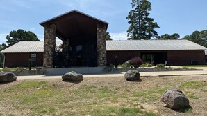 Un lodge rústico con fachada de piedra, un amplio techo saliente y un césped cuidado con rocas.