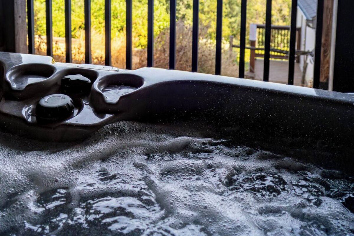 Un jacuzzi con vista a un paisaje verde y un cielo azul despejado.