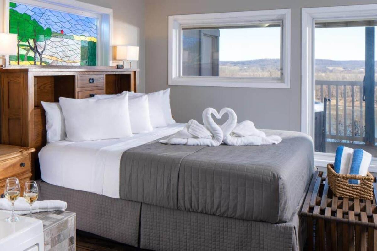 Habitación de hotel con una cama grande, una bañera y vistas al exterior.
