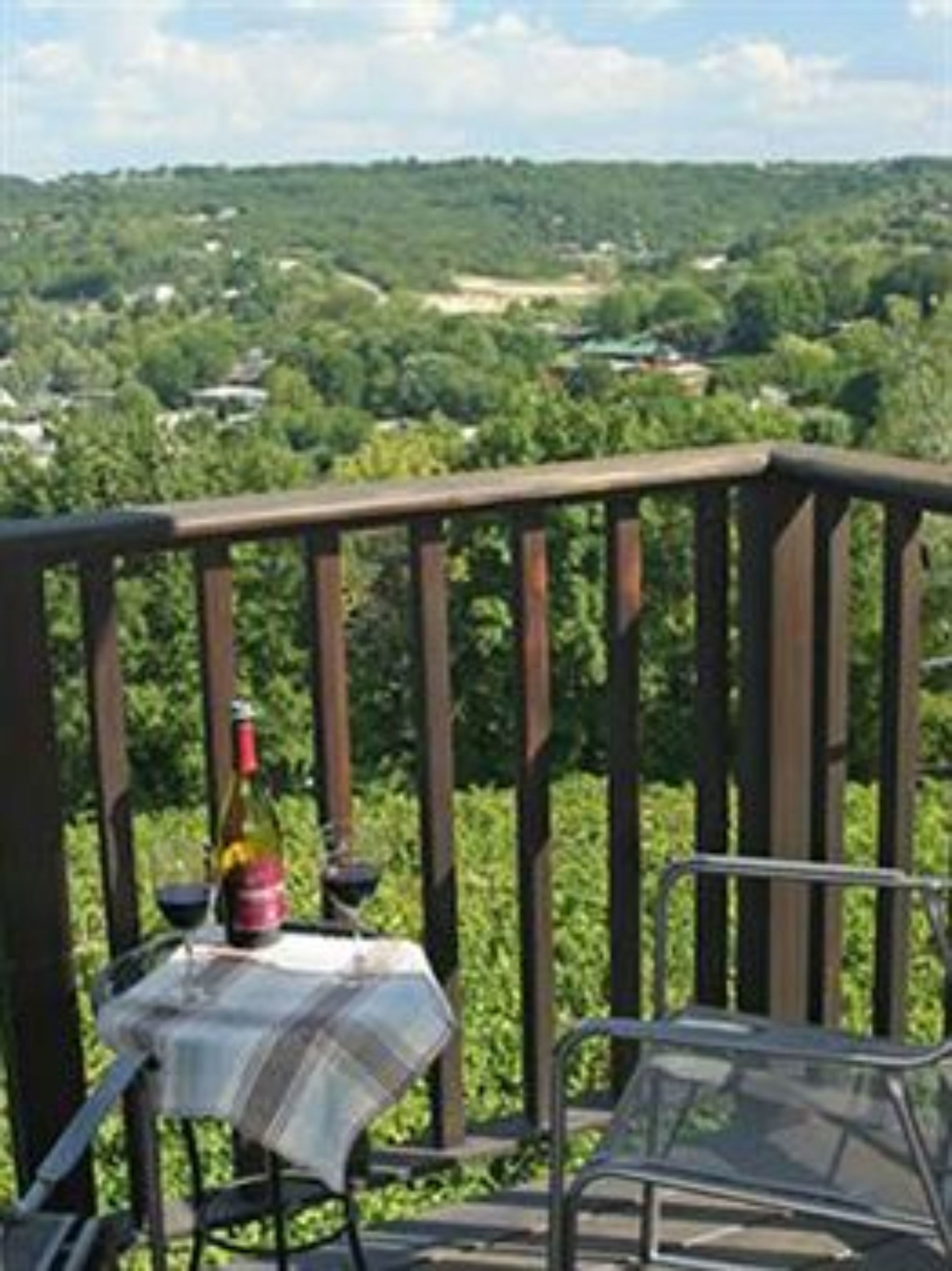 Ein Balkon mit Tisch und Stühlen, mit Blick auf eine grüne Landschaft.