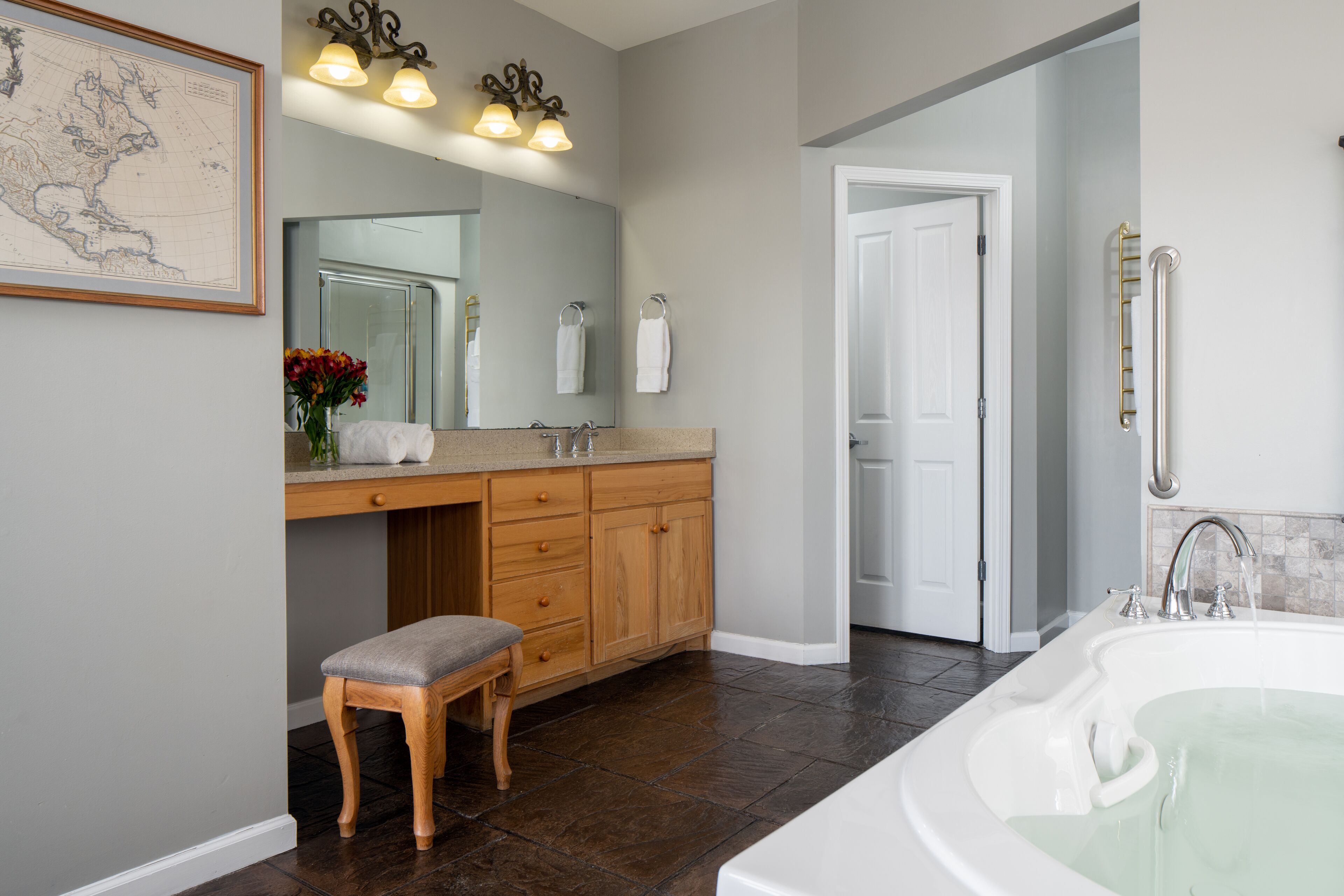 A modern bathroom with a large bathtub, wooden vanity, and a mirror above the sink.