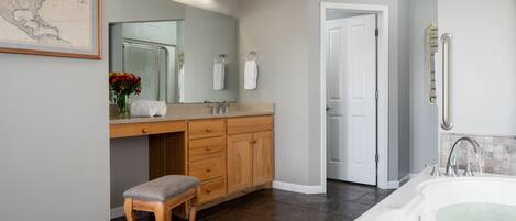 A modern bathroom with a large bathtub, wooden vanity, and a mirror above the sink.