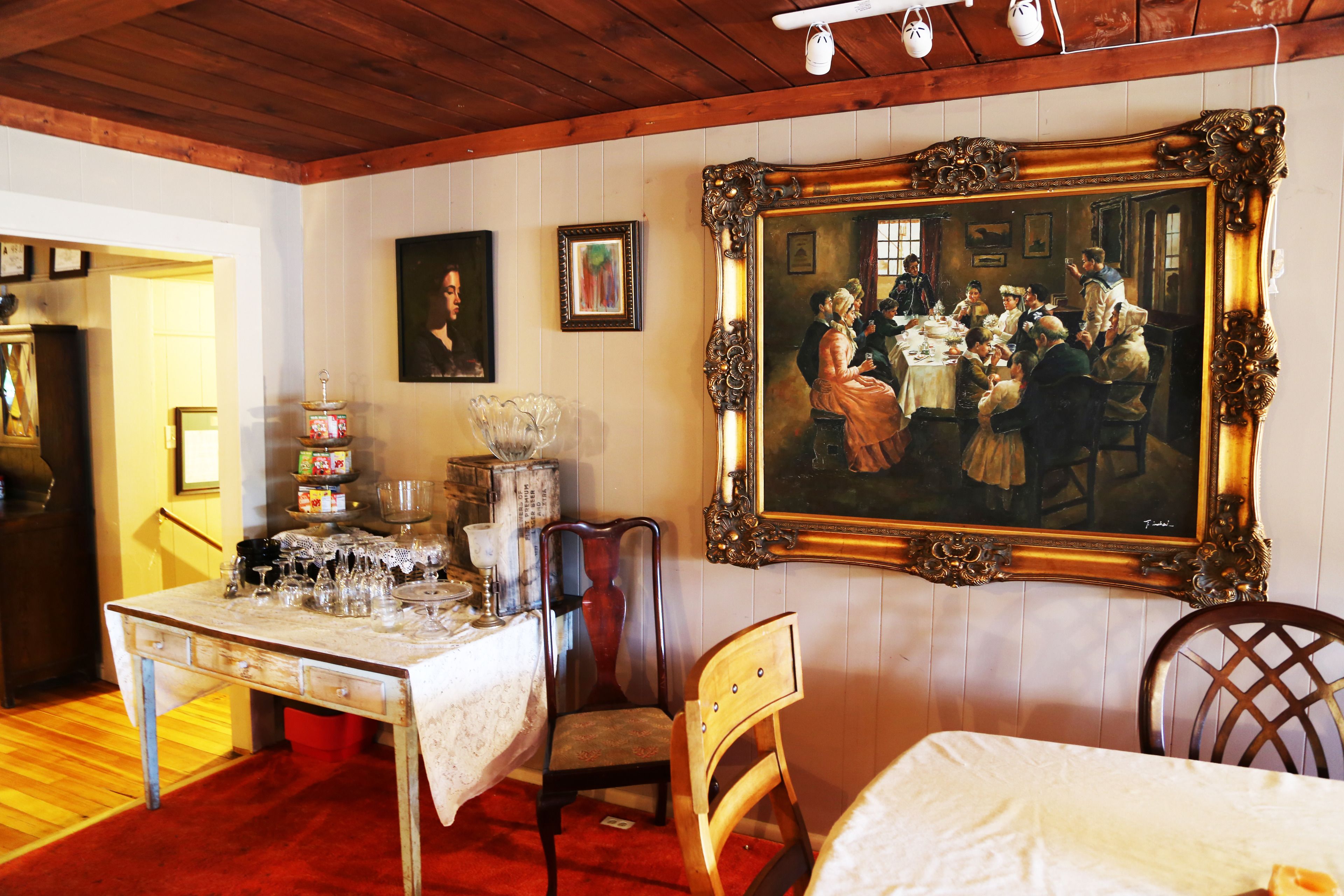 A dining area with a table set for a meal, a large ornate mirror, and a painting on the wall.