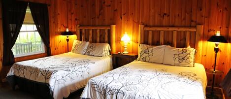 Una habitación con dos camas, paredes de madera y un ventilador de techo.