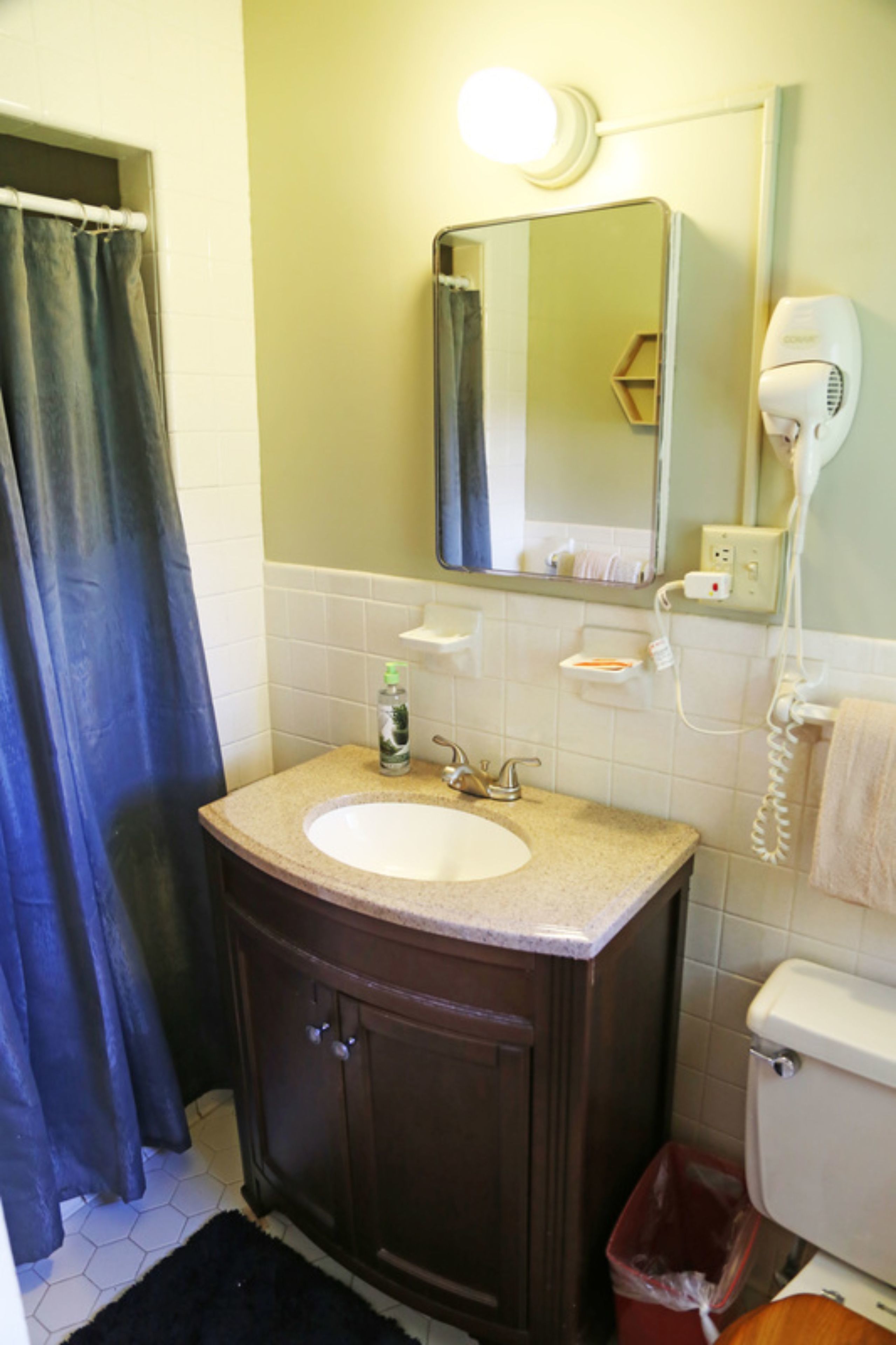 Une salle de bain équipée d’un lavabo, d’un miroir, d’un sèche-cheveux et de toilettes.