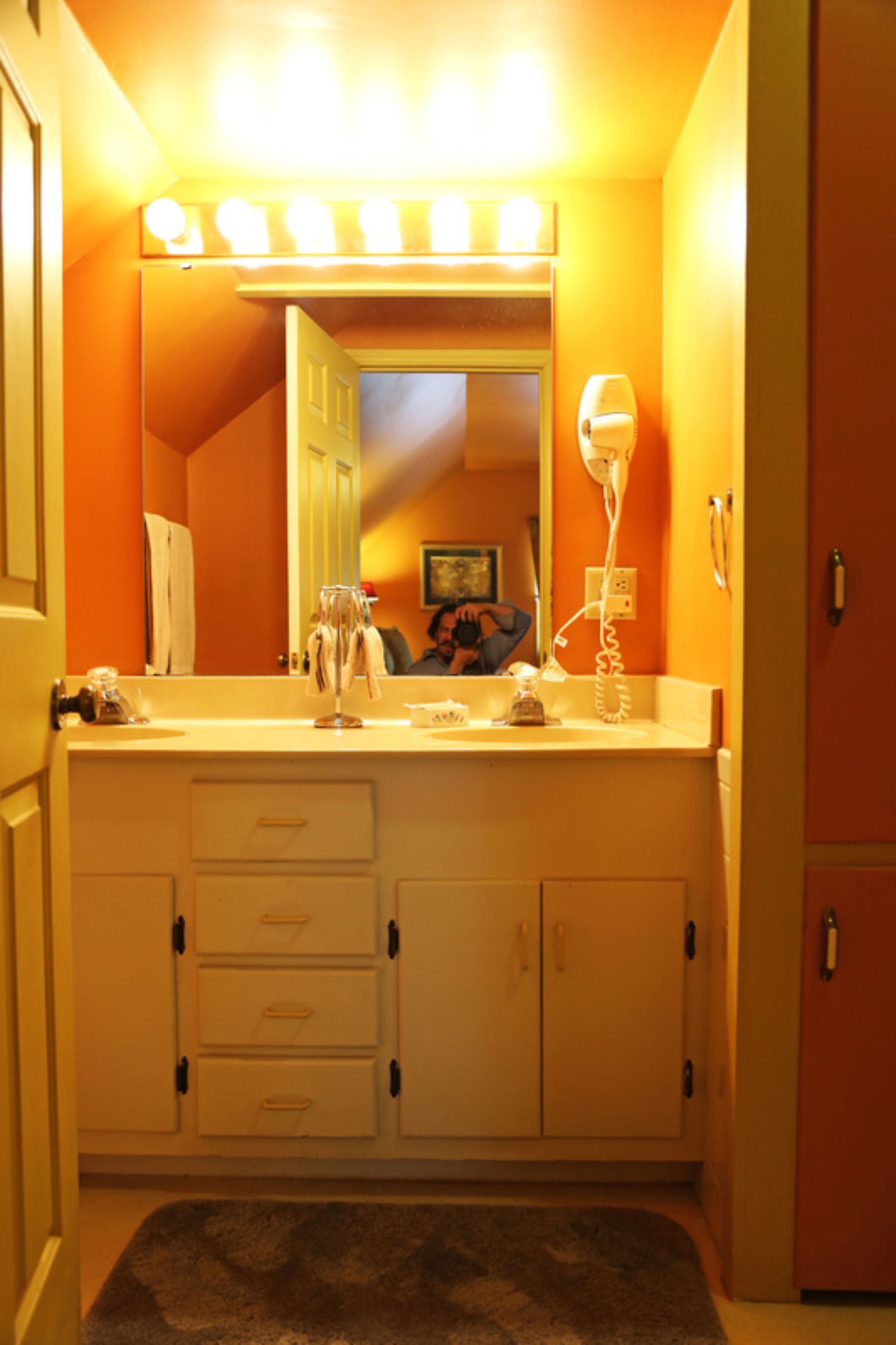A bathroom with a vanity, mirror, and lights.