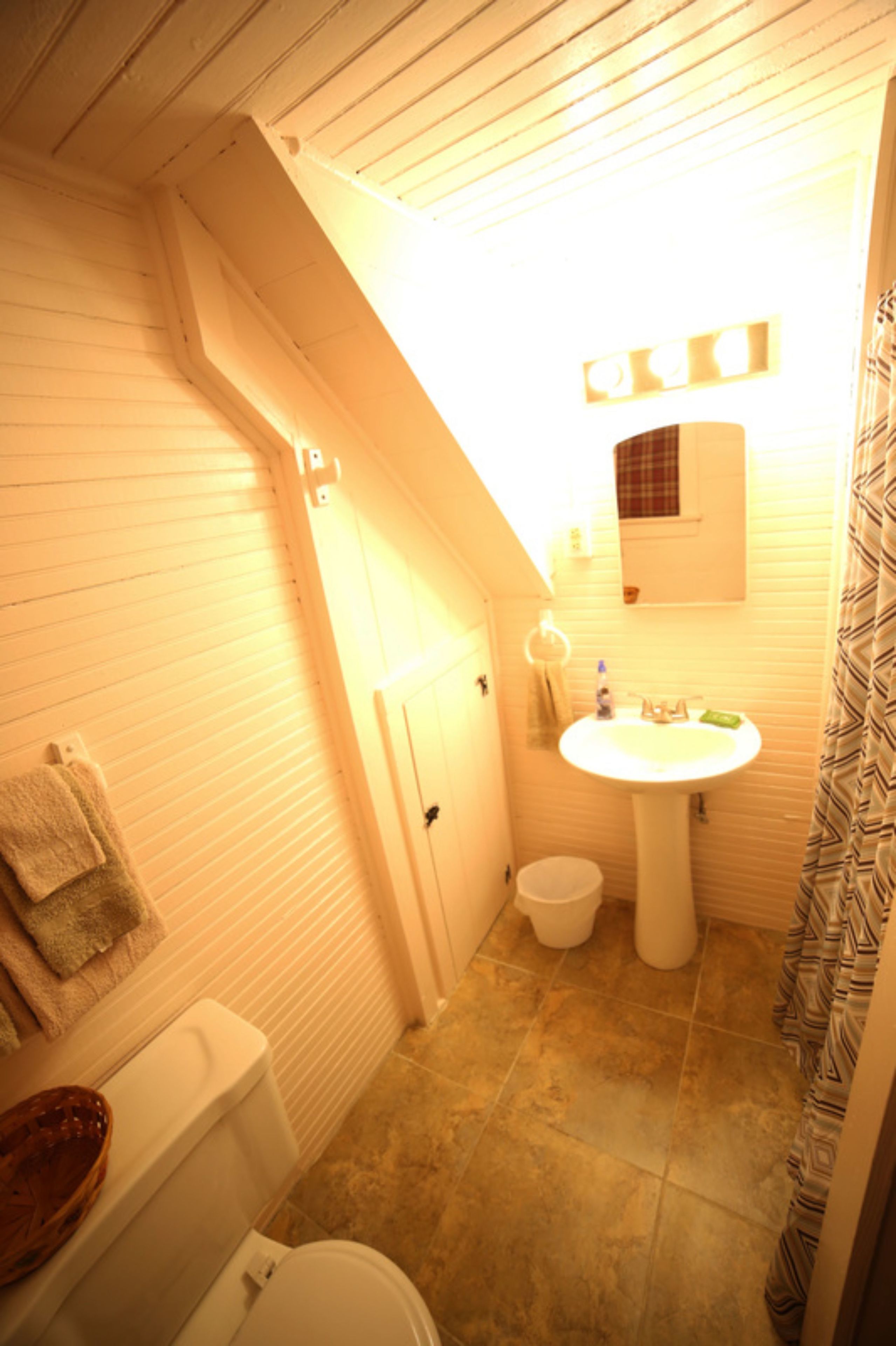 A compact bathroom with a toilet, sink, and shower curtain.
