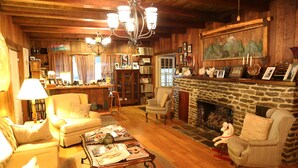 Ein gemütliches Wohnzimmer mit Kamin, Holzmöbeln und einer Bücherwand mit Büchern und Dekorationen.