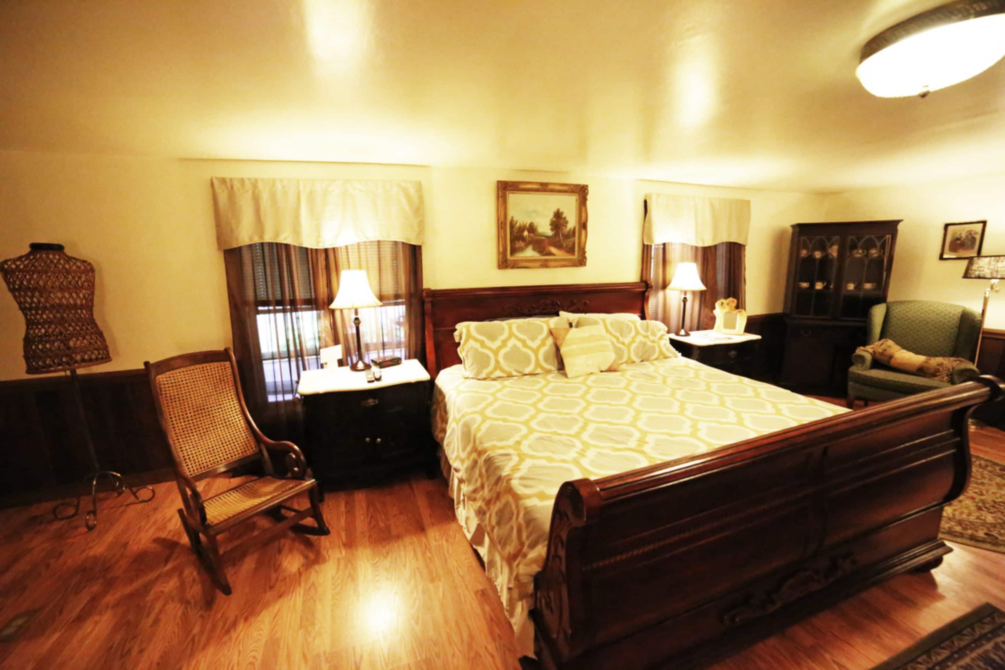 A neatly arranged bedroom with a wooden bed, a chair, a nightstand, and a cabinet.