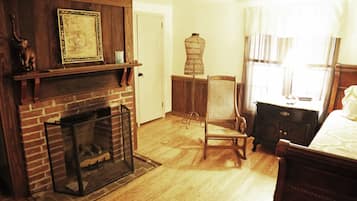 A room with a brick fireplace, a wooden chair, a wooden dresser, and a bed.