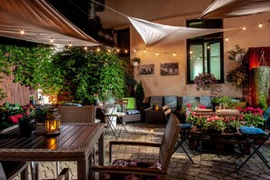An outdoor patio with wicker furniture, string lights, and potted plants. - Spatz Aparthotel (Kraków)