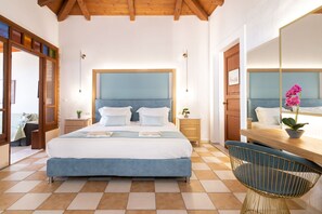 A bedroom with a large bed, bedside tables, a chair, a mirror, and a window with a plant. - Sea View Village - Studios & Apartments (Zakynthos)