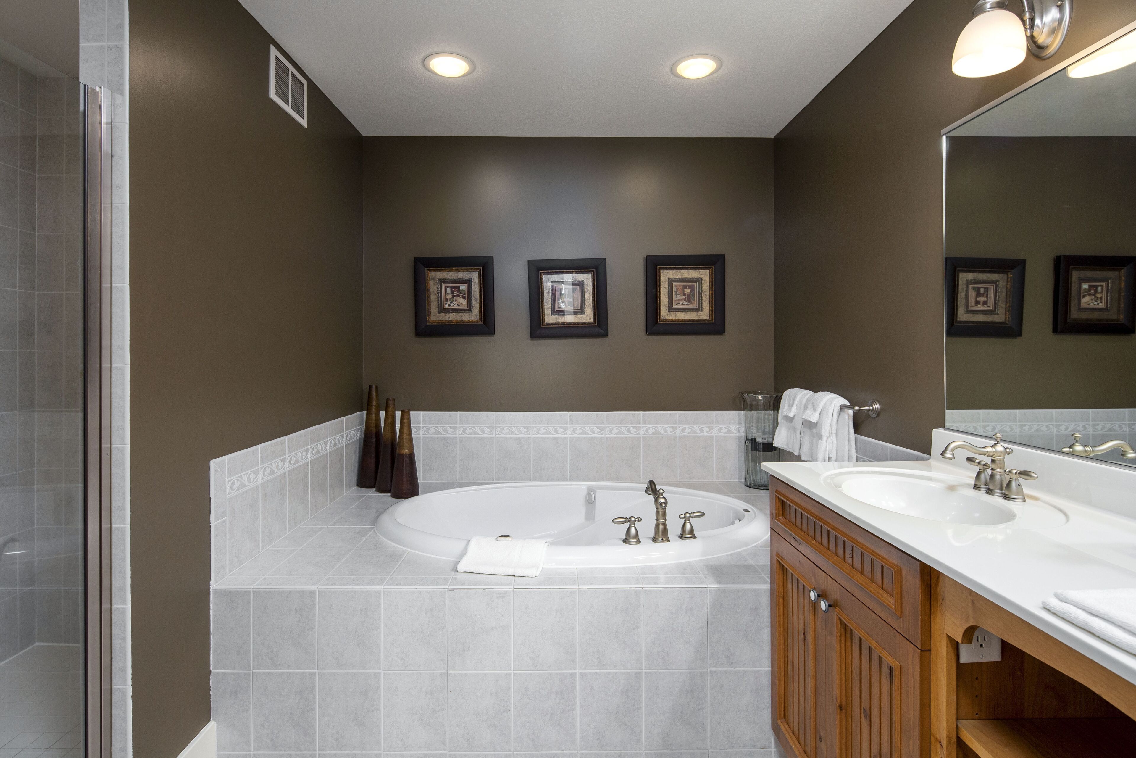 A modern bathroom with a large bathtub, two sinks, and a shower area.