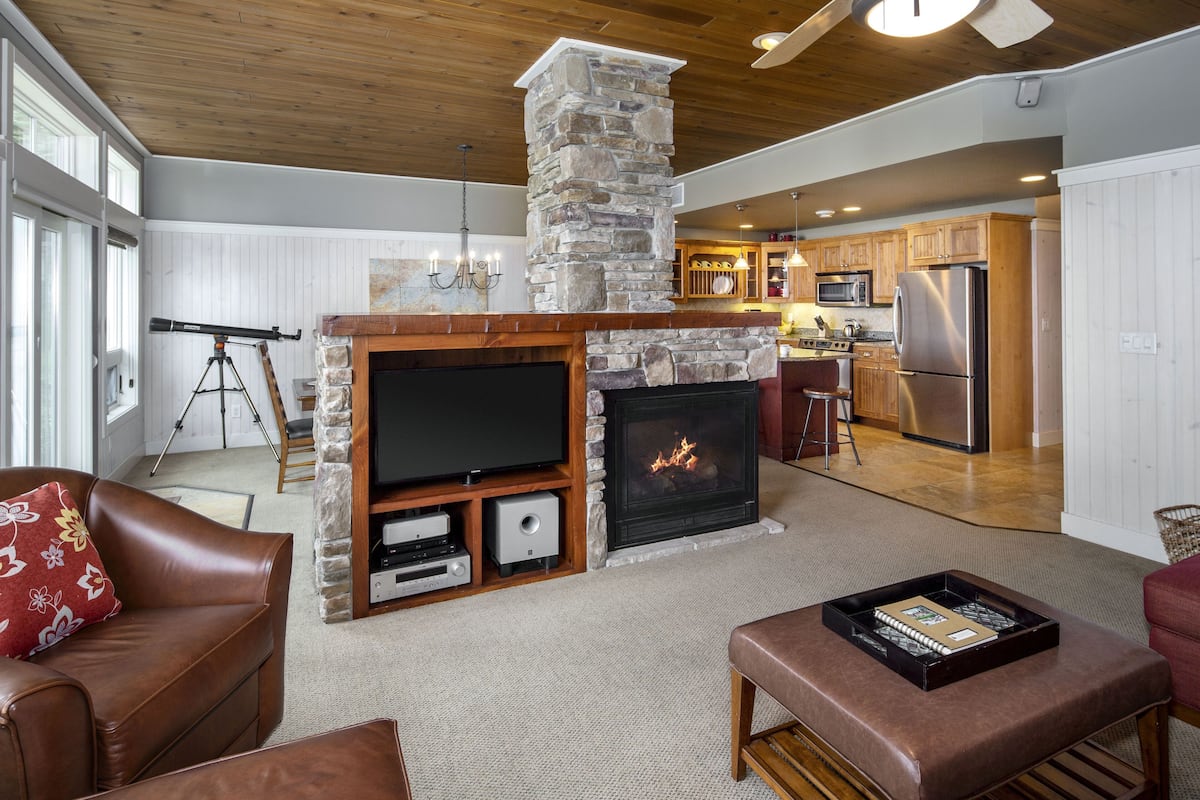 A spacious living room with a stone fireplace, a television, and a cozy seating area.