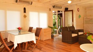 A wooden interior with a dining table, chairs, wicker sofa, and a small table with flowers. - Hotel Villa Monte (Kemer)