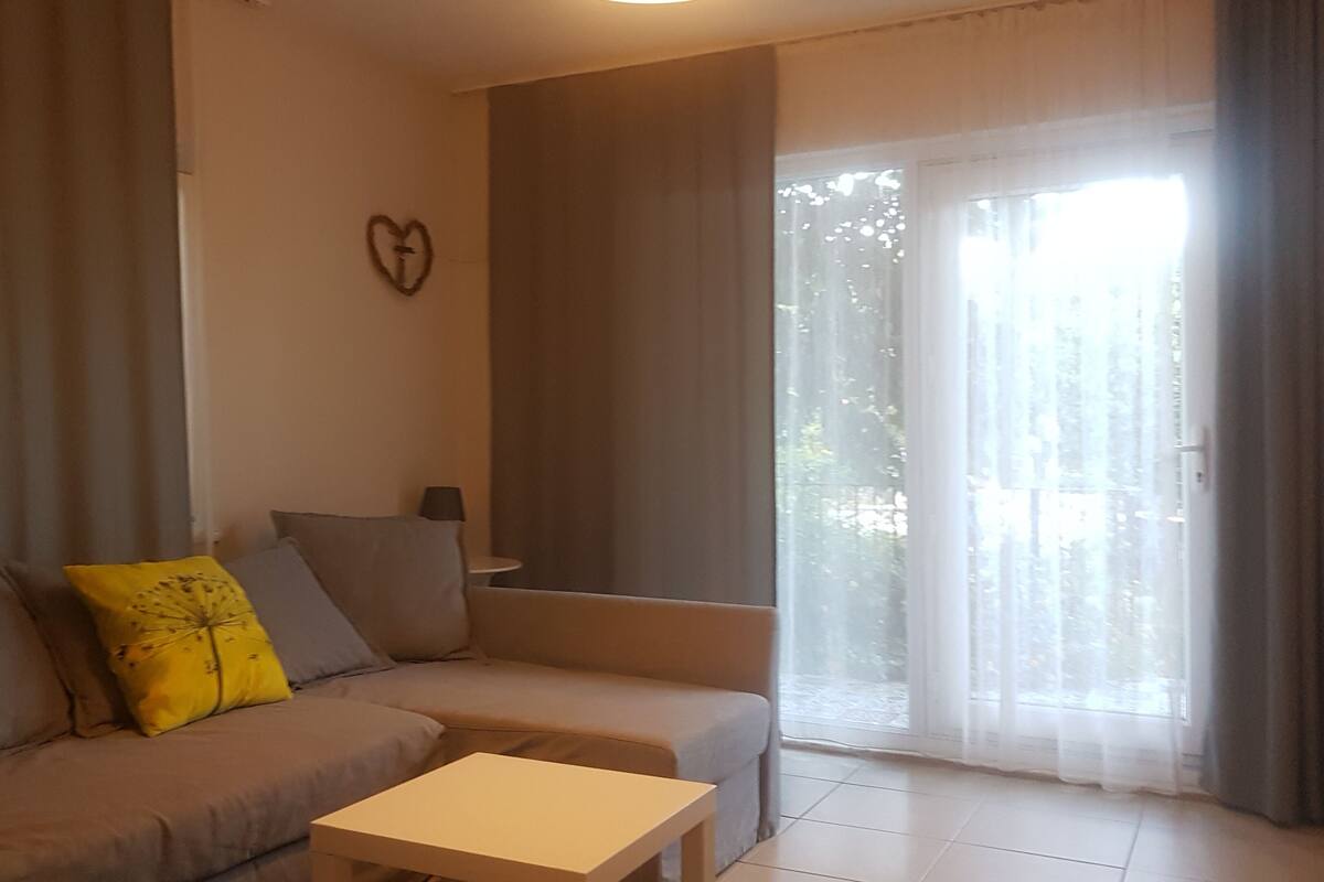 A living room with a sofa, a small table, and a heart-shaped decoration on the wall.