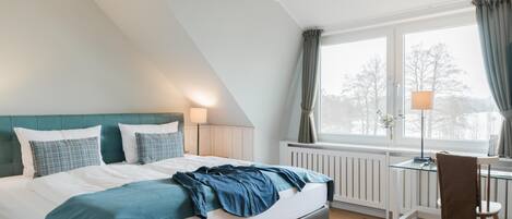 A bedroom with a bed, a desk, and a window with curtains.
