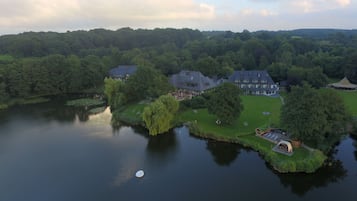 Vue aérienne d’une propriété au bord du lac, comprenant plusieurs grandes maisons, une pelouse bien entretenue et un petit quai.