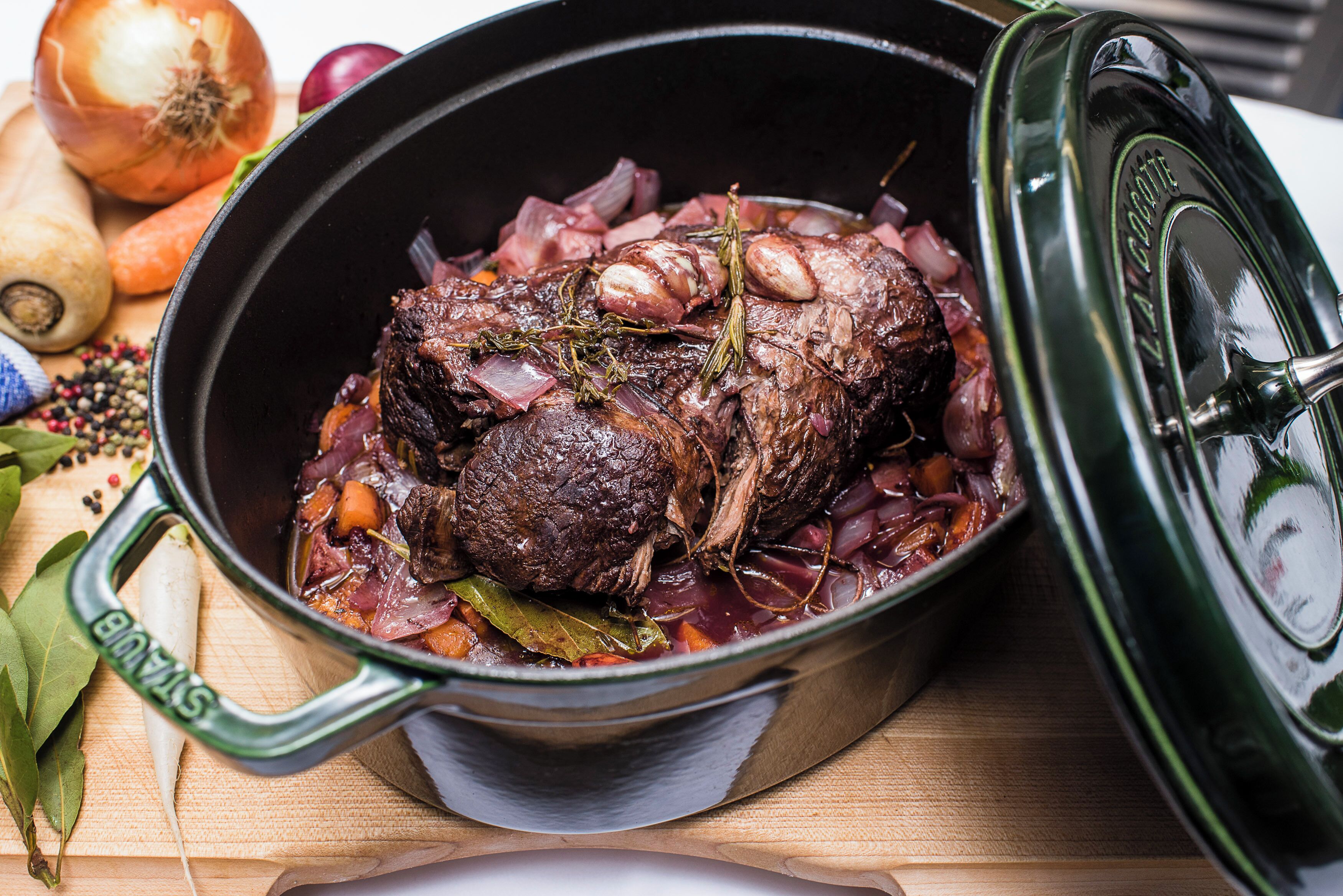 A pot of braised beef with vegetables and herbs.