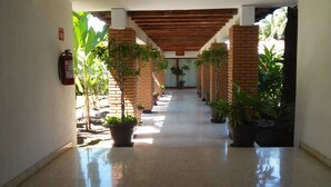 A corridor with brick pillars, potted plants, and a fire extinguisher on the wall. - Hotel Kamico (Tapachula)