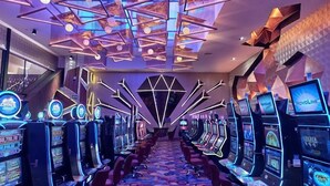 A row of slot machines in a casino with a geometric ceiling design. - Hotel Kamico (Tapachula)