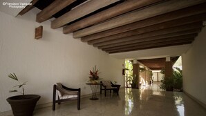 A spacious hallway with a polished floor, wooden beams, and potted plants. - Hotel Kamico (Tapachula)