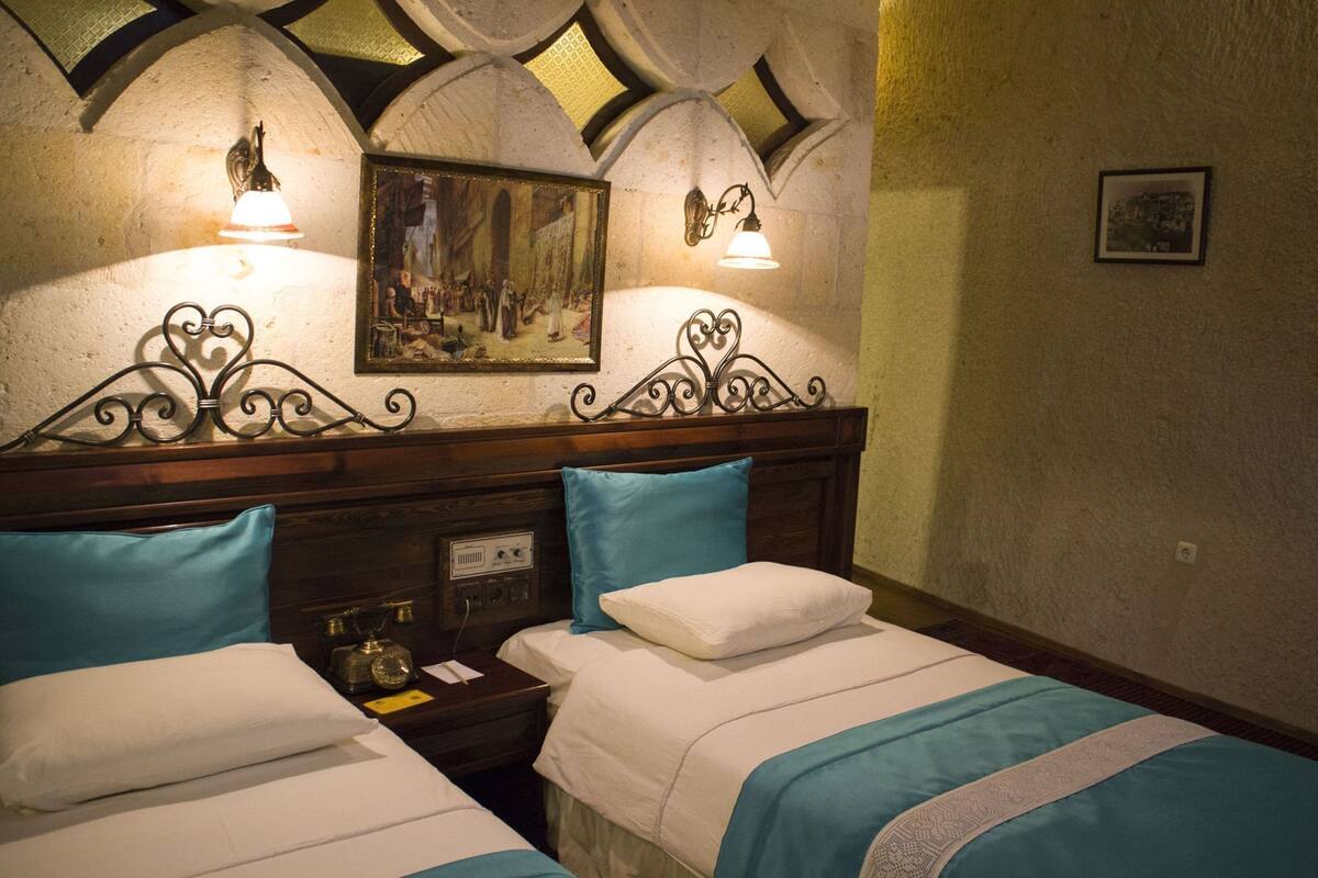 Ein Hotelzimmer mit zwei Betten, einem Bild an der Wand und Wandleuchten.