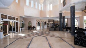A spacious lobby with high ceilings, arched doorways, and a central marble floor design.