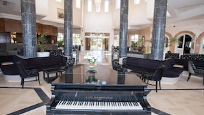 A grand lobby with a grand piano, marble columns, and a spacious seating area.