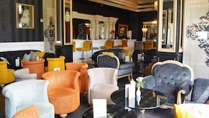 A lobby with a variety of seating options including sofas and armchairs, a reception desk, and a decorative mirror.