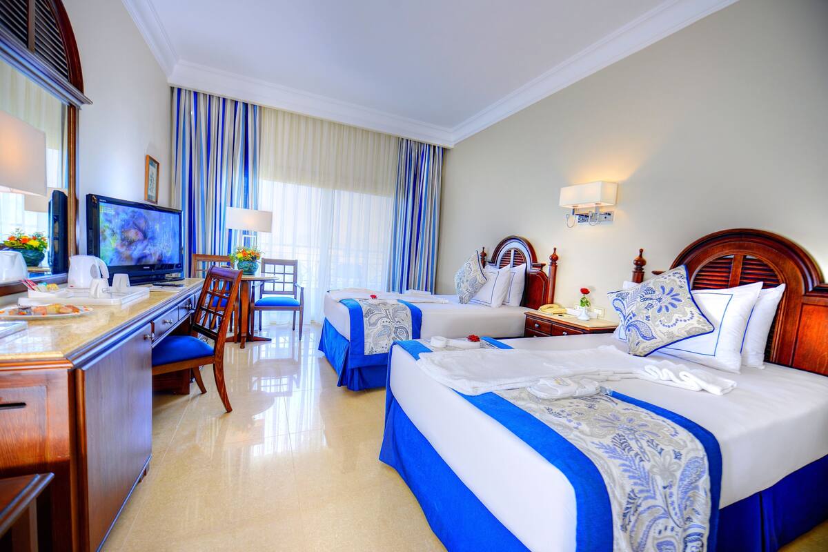 Une chambre d’hôtel avec deux lits, un bureau, une télévision et un coin repas.