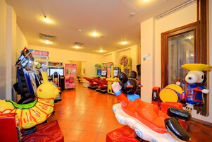 Un salón de juegos interior con varias máquinas recreativas y un juguete inflable grande.
