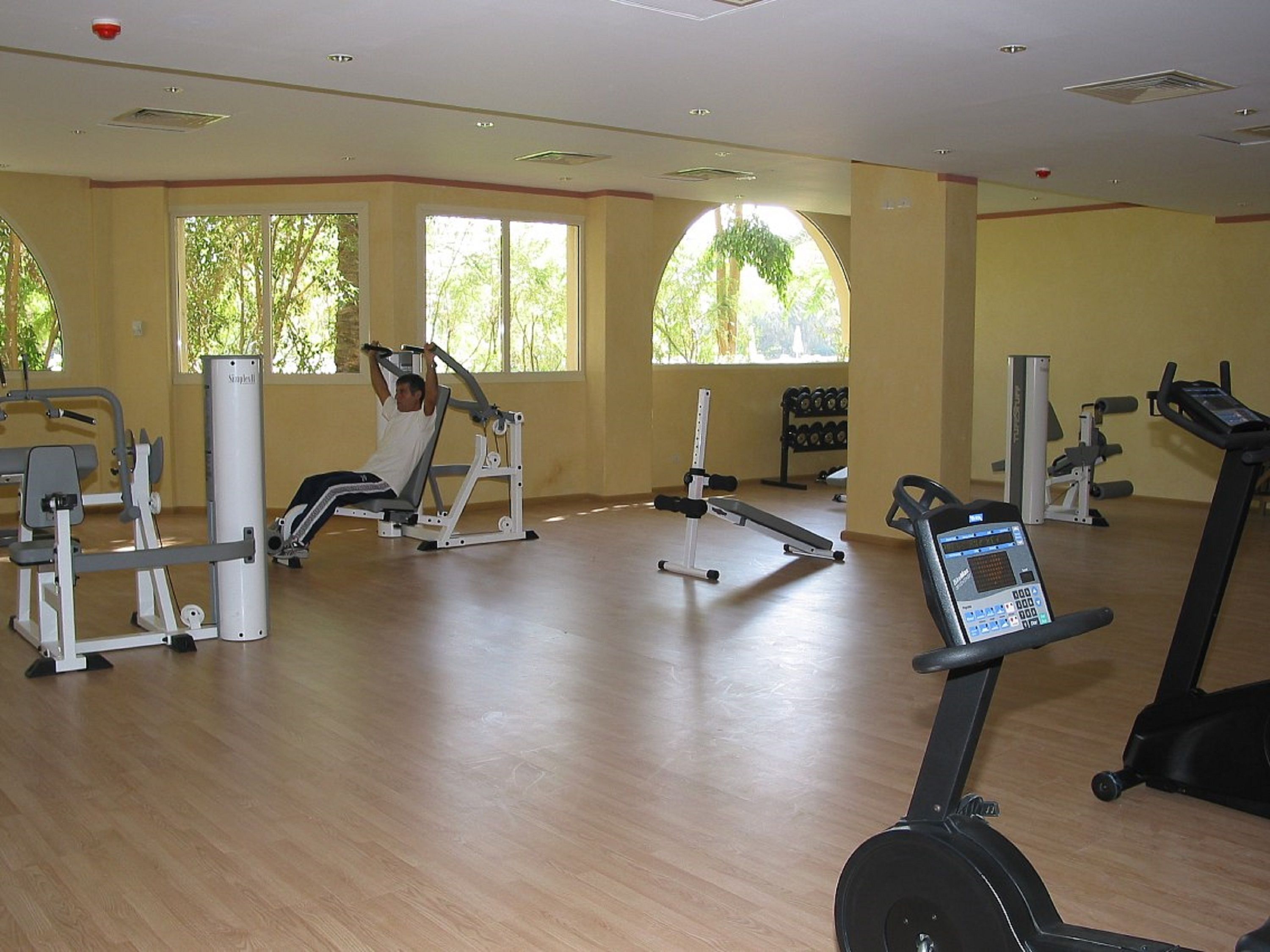 A gym with cardio machines, weight stations, and dumbbells.
