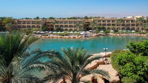 Een resort met een groot zwembad, palmbomen en een gebouw met meerdere balkons.