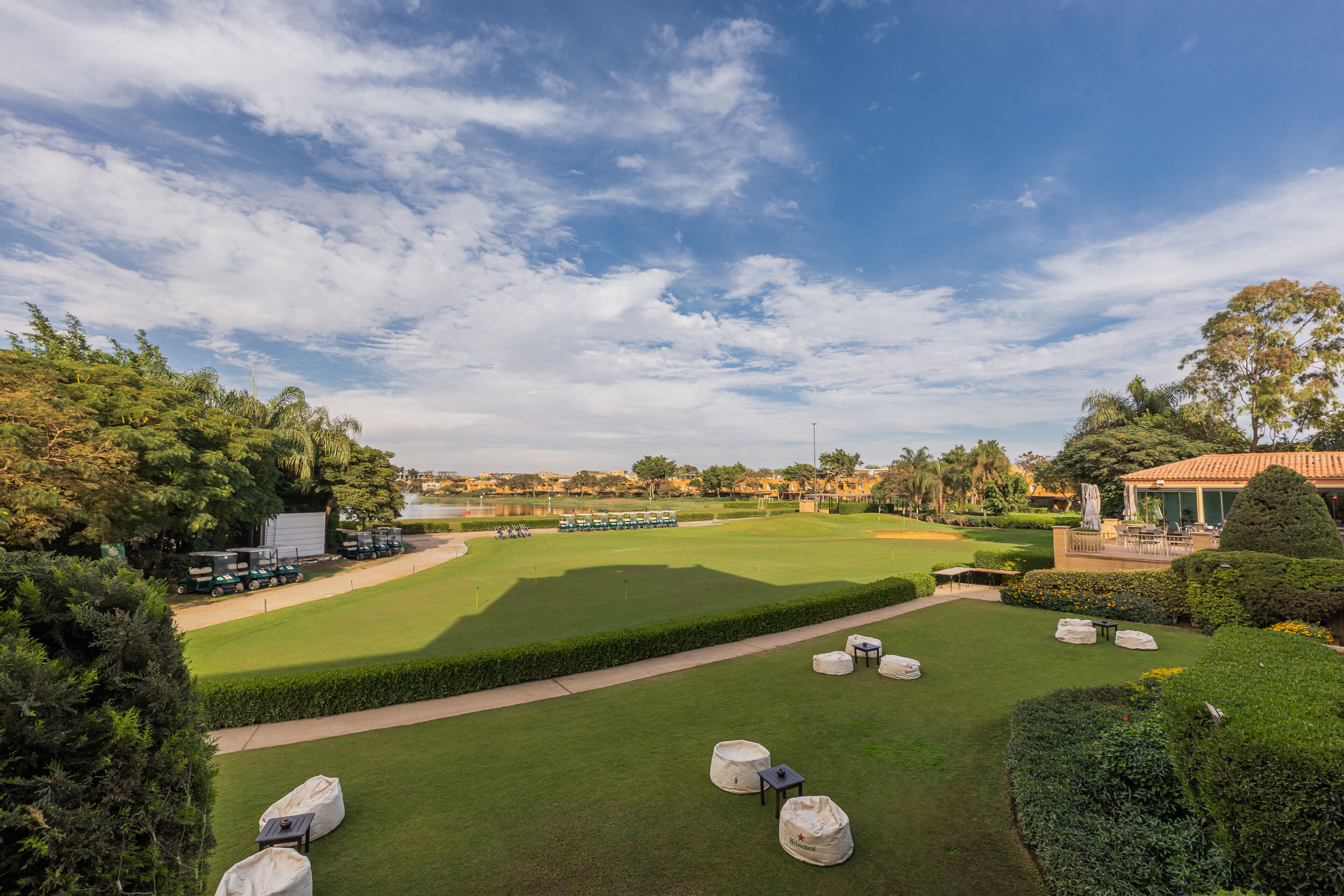 Un parcours de golf avec une pelouse soigneusement entretenue, une haie bien taillée et un ciel dégagé.