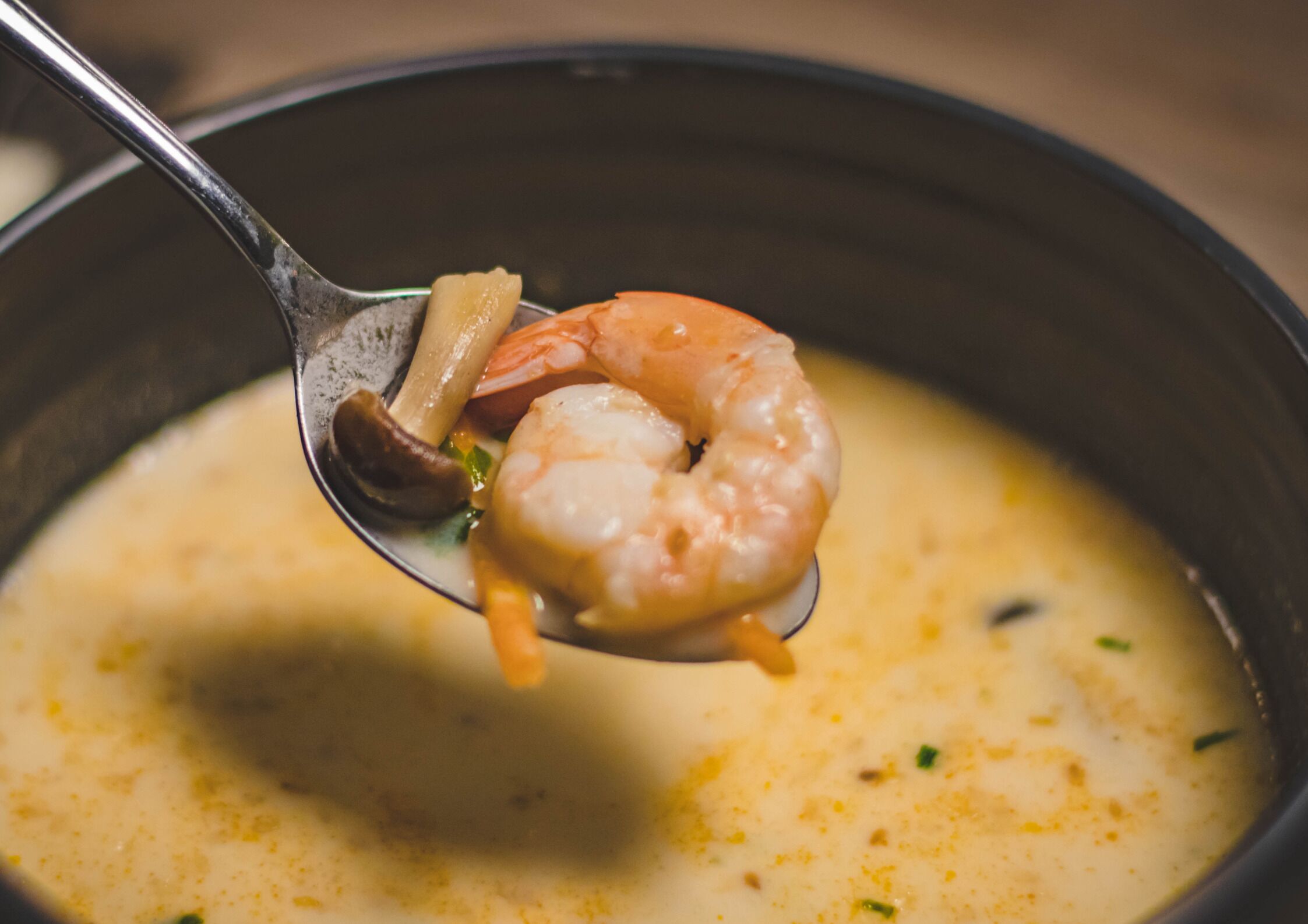 A spoonful of soup with shrimp and vegetables.
