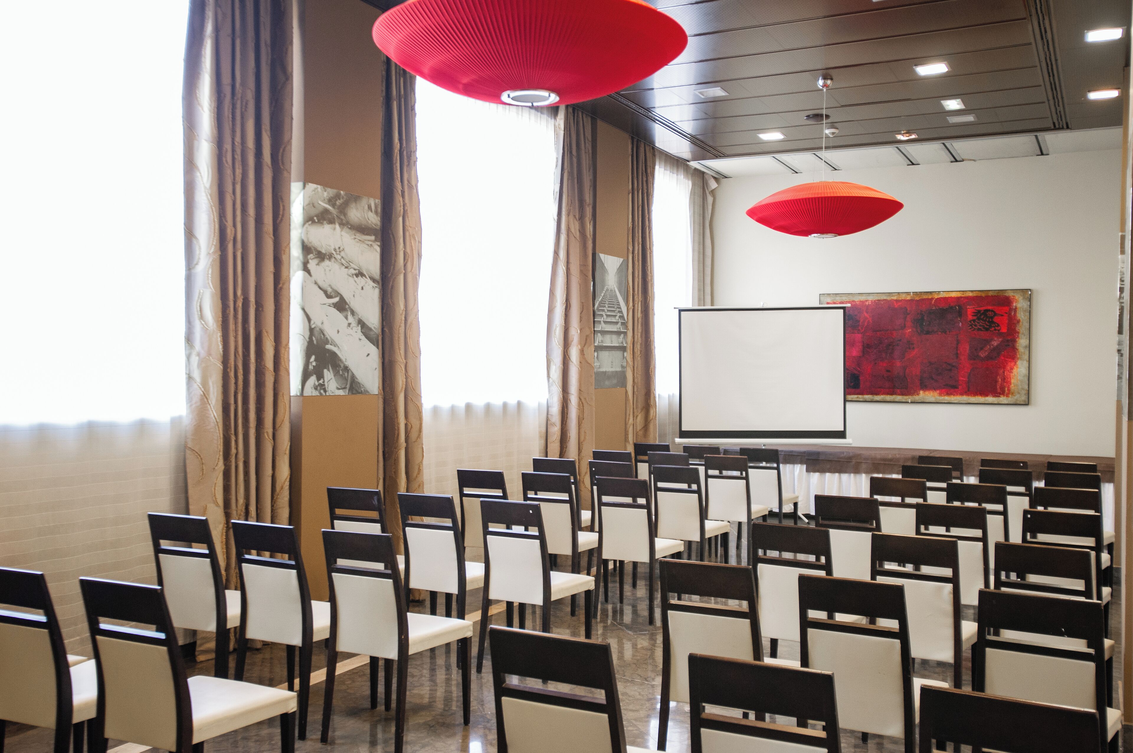 A conference room with rows of chairs, a whiteboard, and a large abstract painting on the wall.