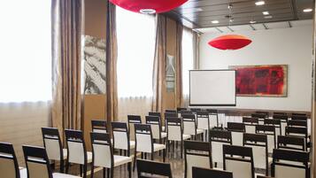 A conference room with rows of chairs, a whiteboard, and a large abstract painting on the wall.
