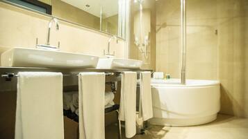 A modern bathroom with a large sink, a separate bathtub, and a glass-enclosed shower.