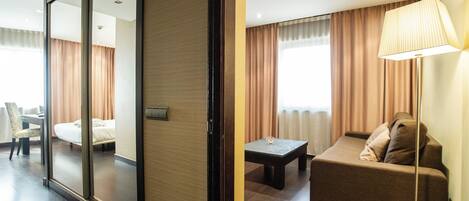 A hotel room with a sliding door, a sofa, a table, and a lamp.