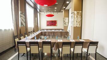 A conference room with a long table, chairs, and red pendant lights.