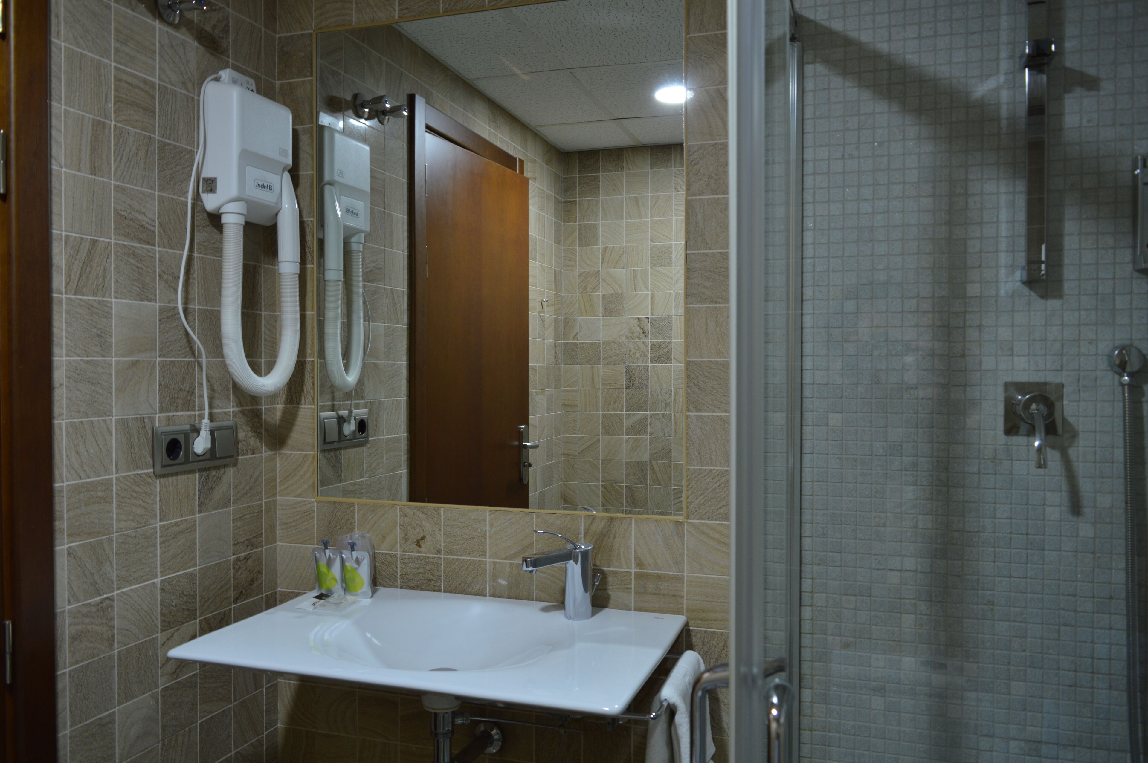 A bathroom with a sink, mirror, and shower.