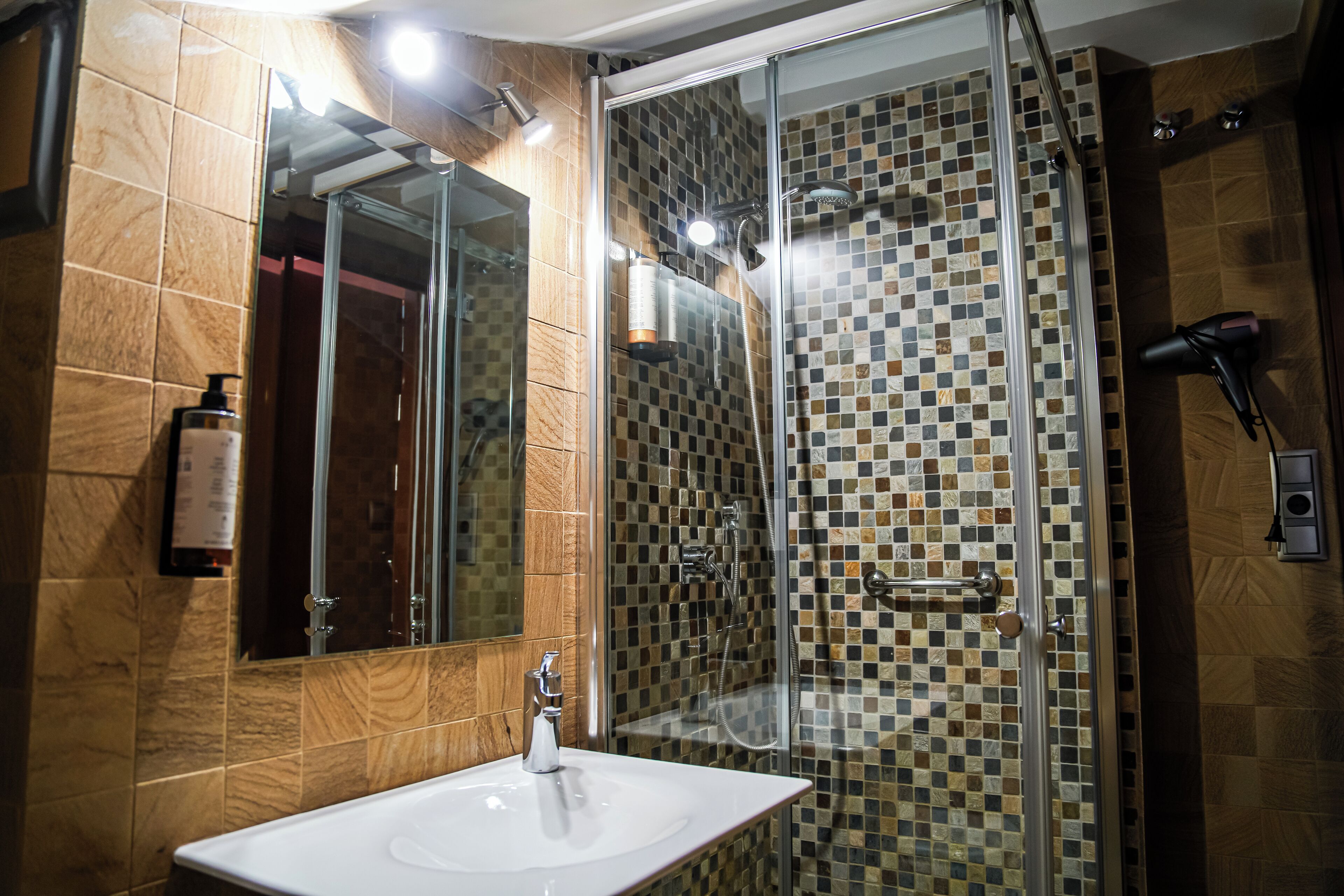 A bathroom with a glass-enclosed shower, a sink, and a mirror.