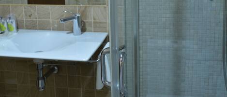 A bathroom with a glass shower enclosure, a sink with a mirror, and a towel rack.