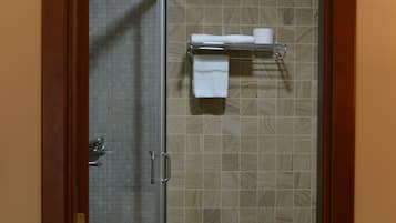 Un baño con mampara de vidrio, inodoro y repisa con toalla.