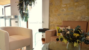 A modern living room with a sofa, a glass coffee table, and a vase with flowers. - Hotel Baeza Monumental by eme Hoteles (Baeza)