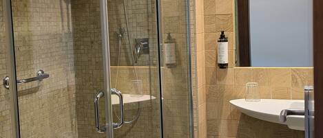 A modern bathroom with a glass-enclosed shower, a white sink, and a mirror.